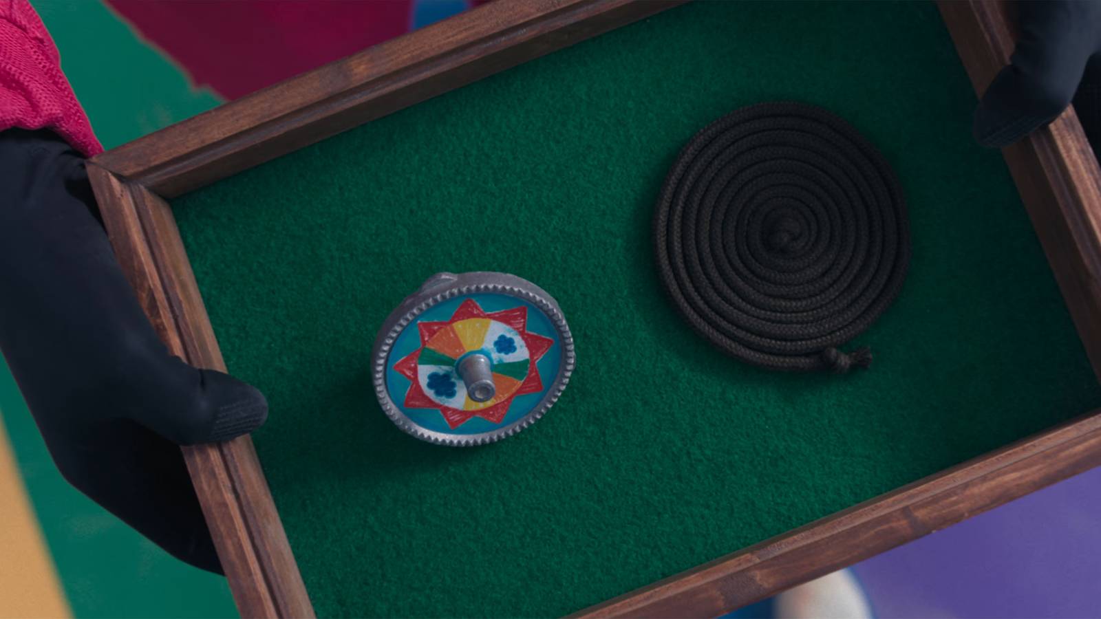 A Paengi Chigi spinning top and a coil of twine presented inside a green felt box in Squid Game.