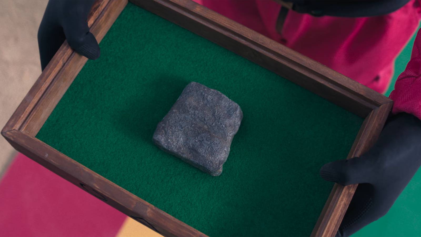 The Flying Stone gets presented in a green felt box by a guard in Squid Game.