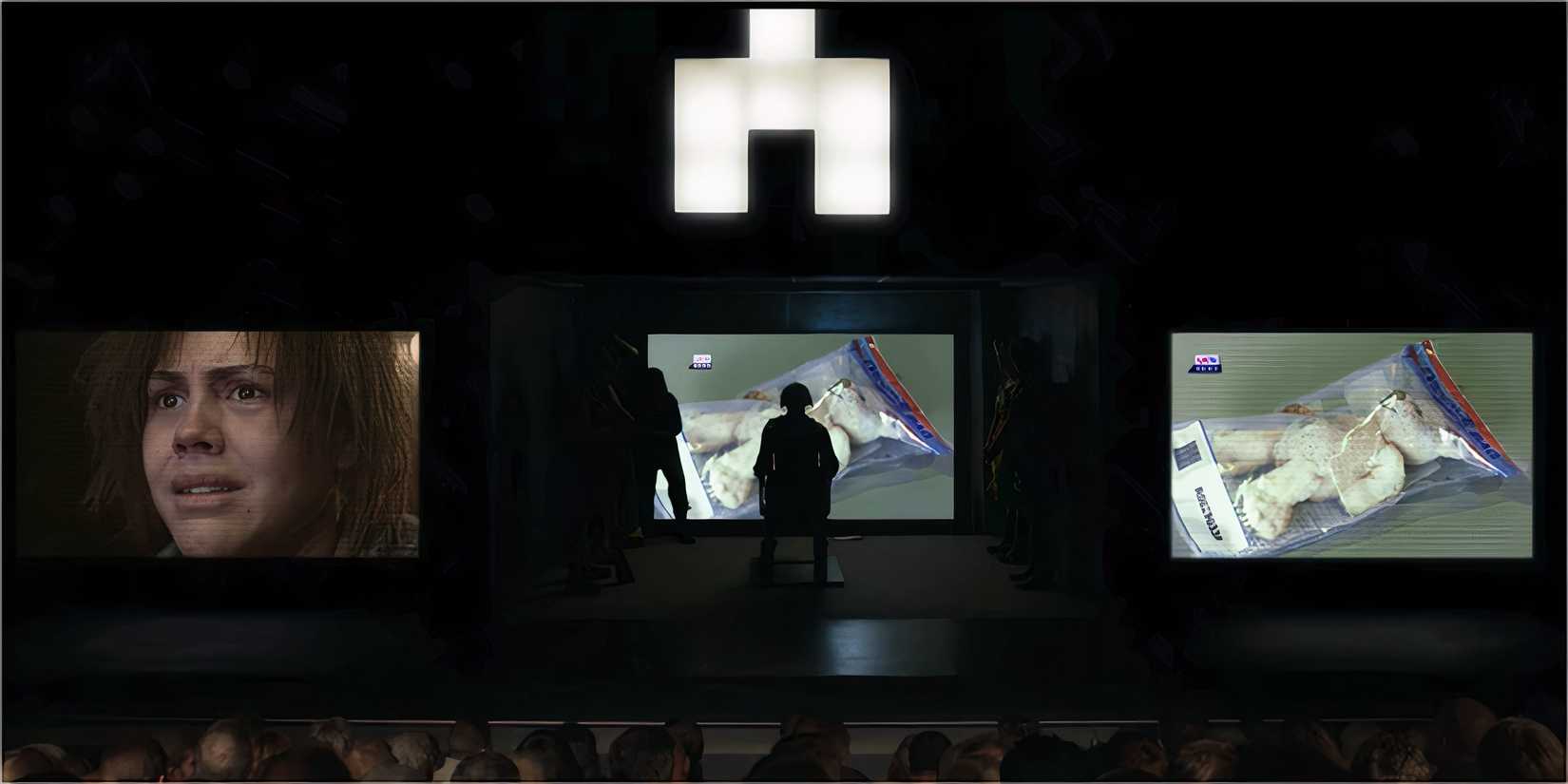 A woman on stage, projected on large screens as a crowd watches.