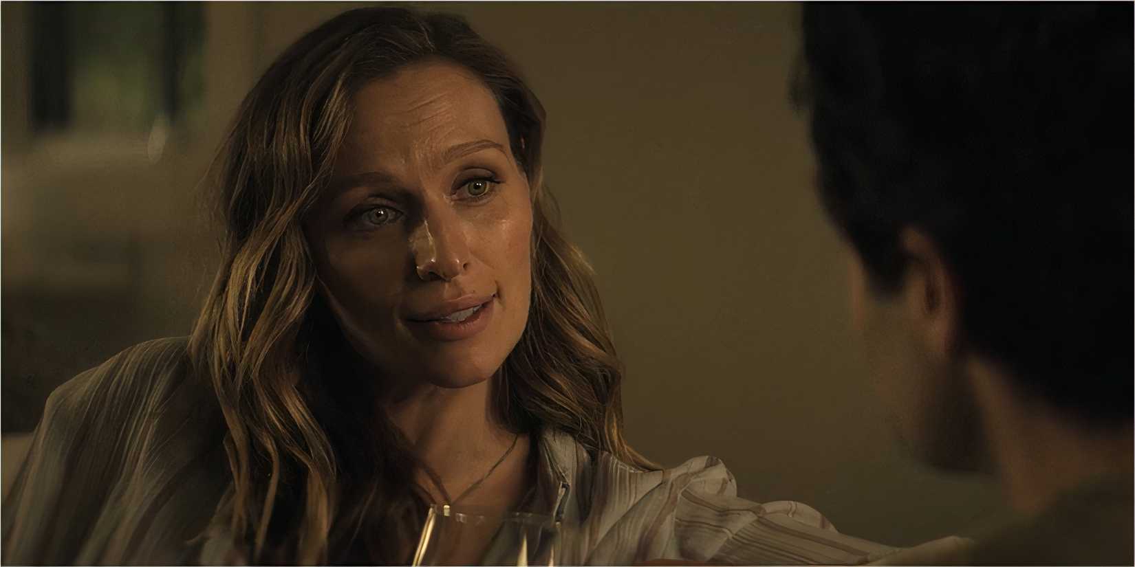 A woman smiles faintly while holding a glass