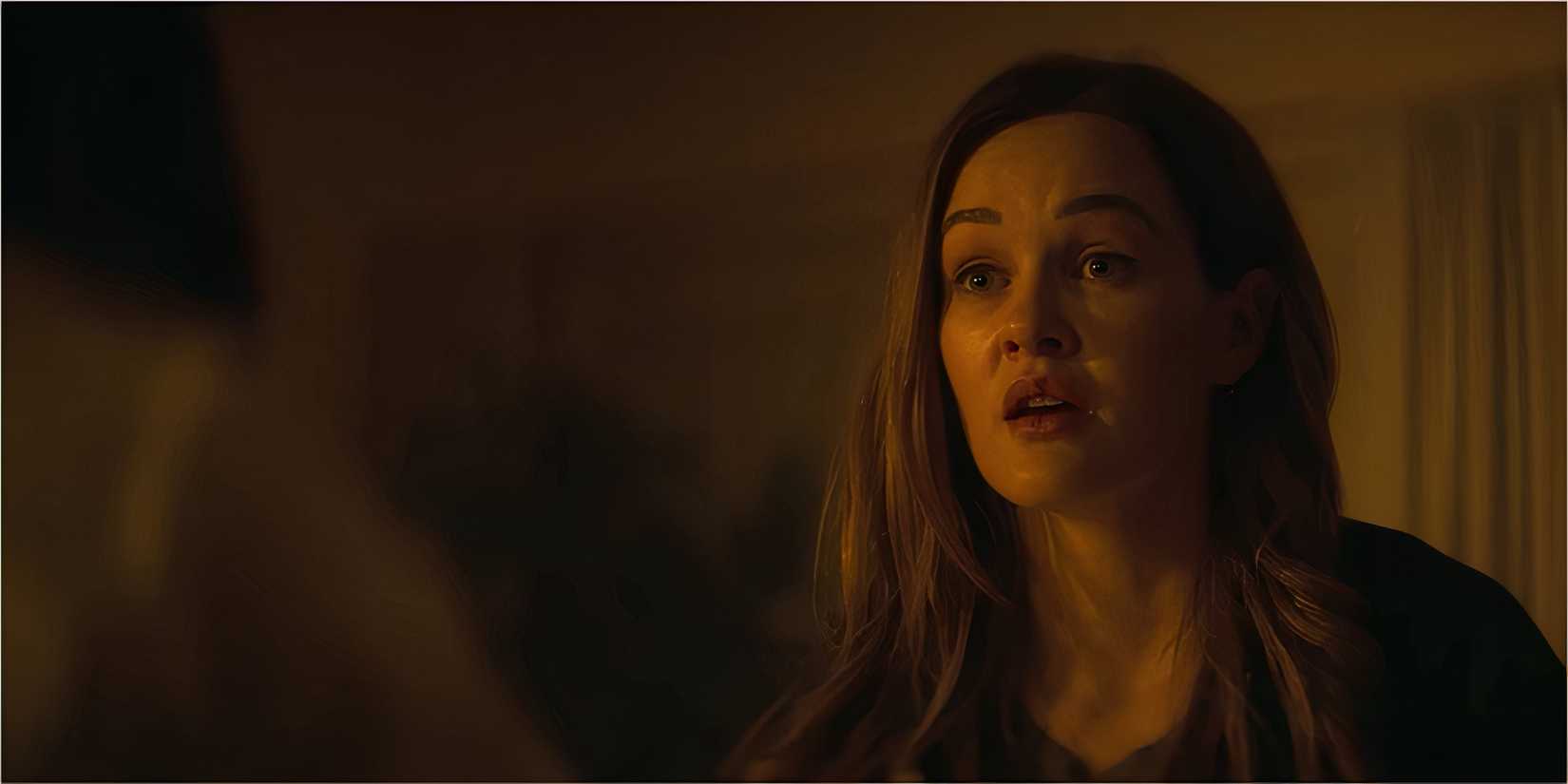 A woman with long hair looks stunned under warm lighting