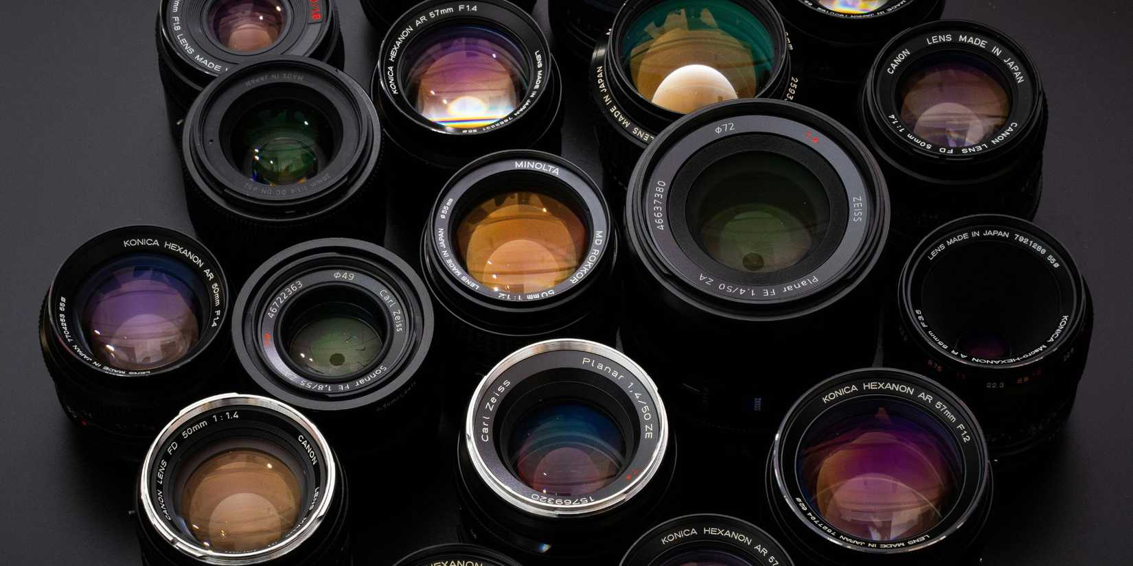 Image of various camera lenses placed next to each other on a black background.