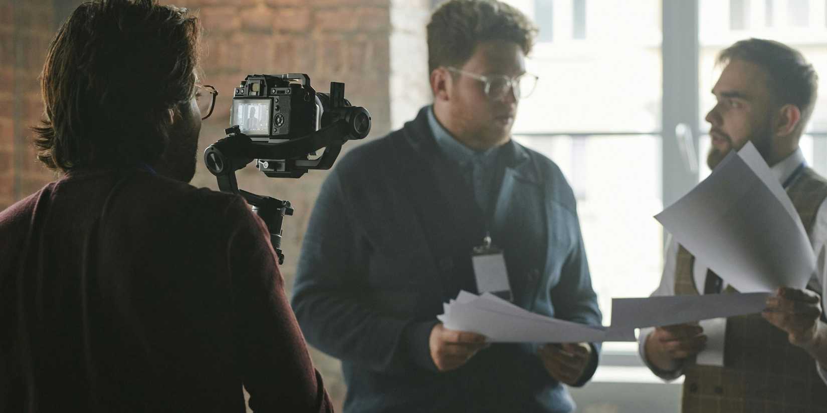 Image of a man shooting a video of an interview going on.