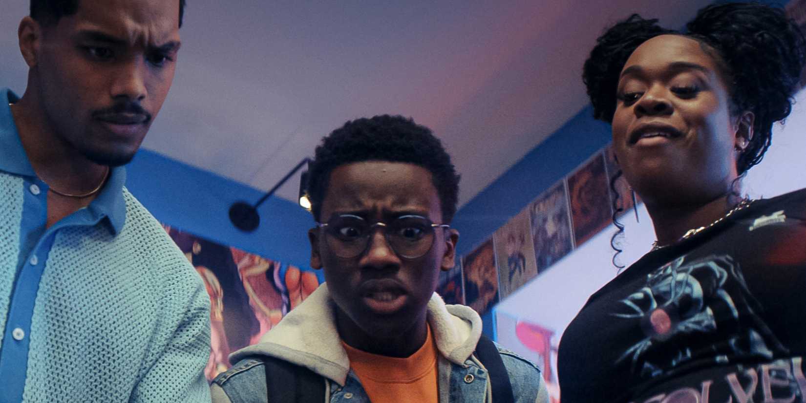 A still from Side Quest episode "Pull List" with three characters in a line standing in a comic book store looking down at a single issue of a Mythic Quest comic book issue