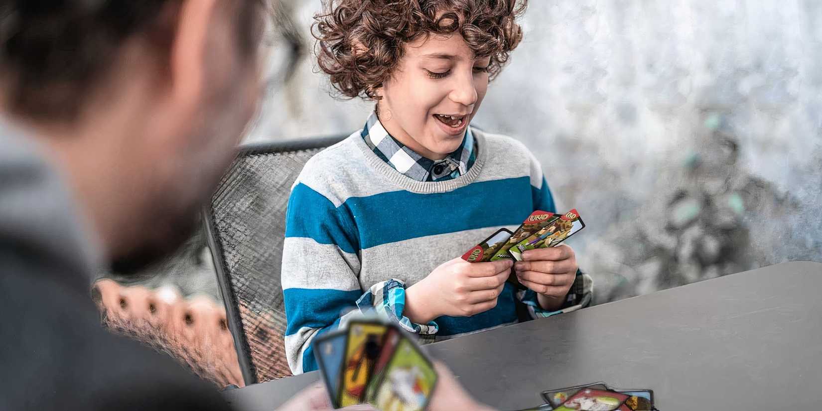Stock image of an adult and a kid playing the minecraft edition of UNO on a table. They seem happy :)
