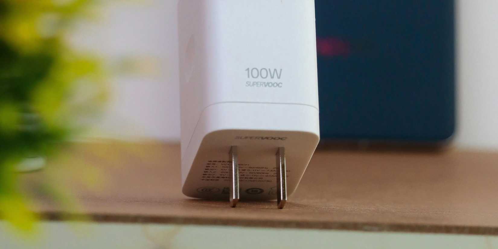 Image of a 100W fast charger on a wooden table. 