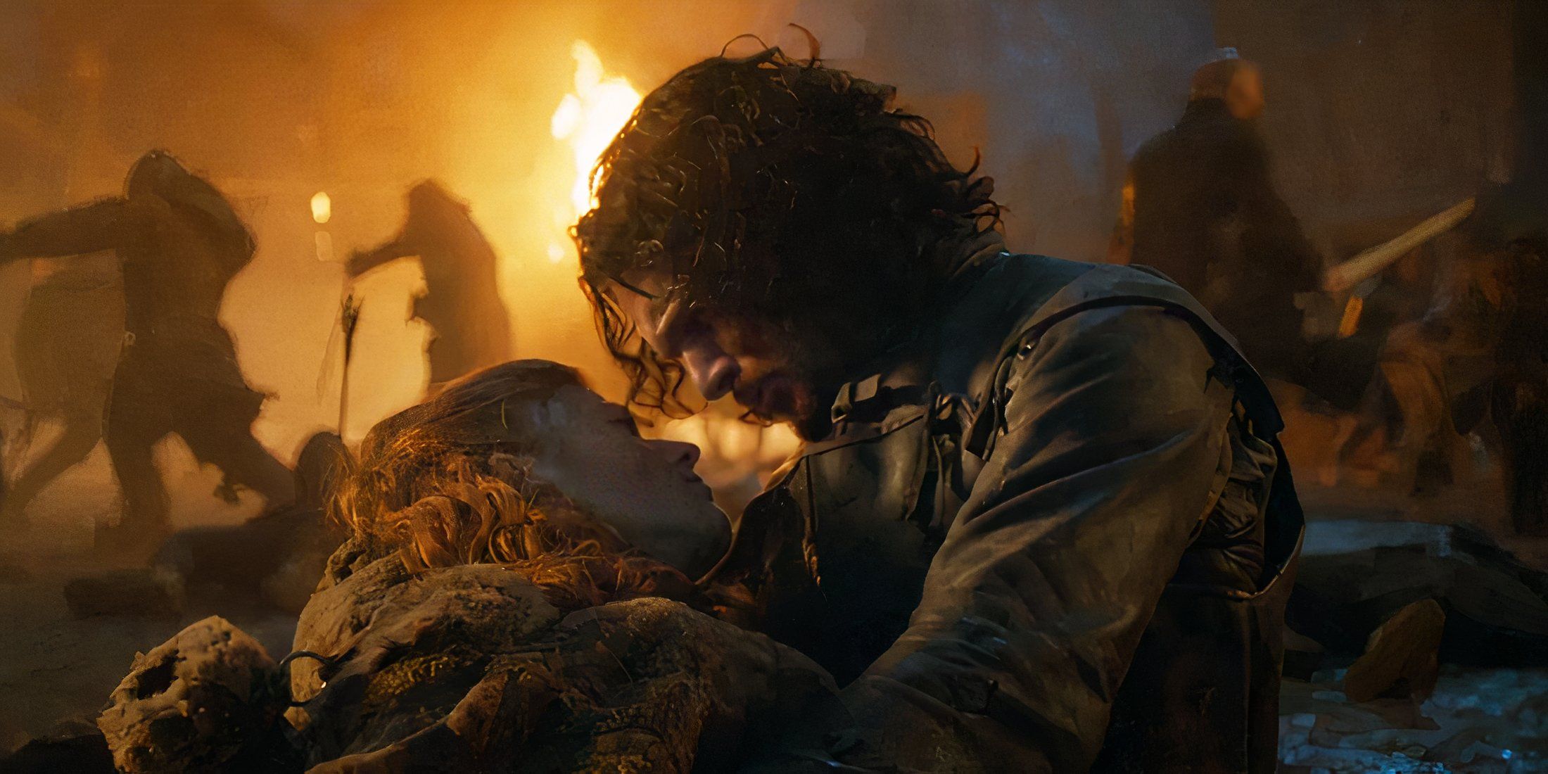 Jon Snow holding a dead Ygritte while fighting goes on in the background in Game of Thrones