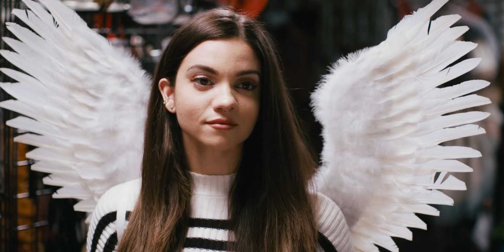 Lauren Le Vera as Sienna Shaw in a white and black striped sweatshirt and angel wings