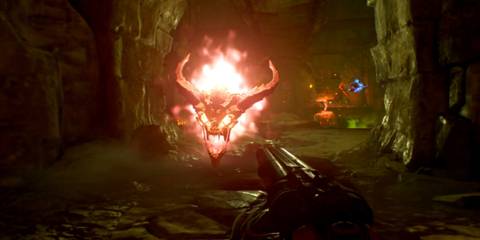 A flaming, horned demon head floats menacingly toward the player in a hellish cavern in Doom (2016) on Switch