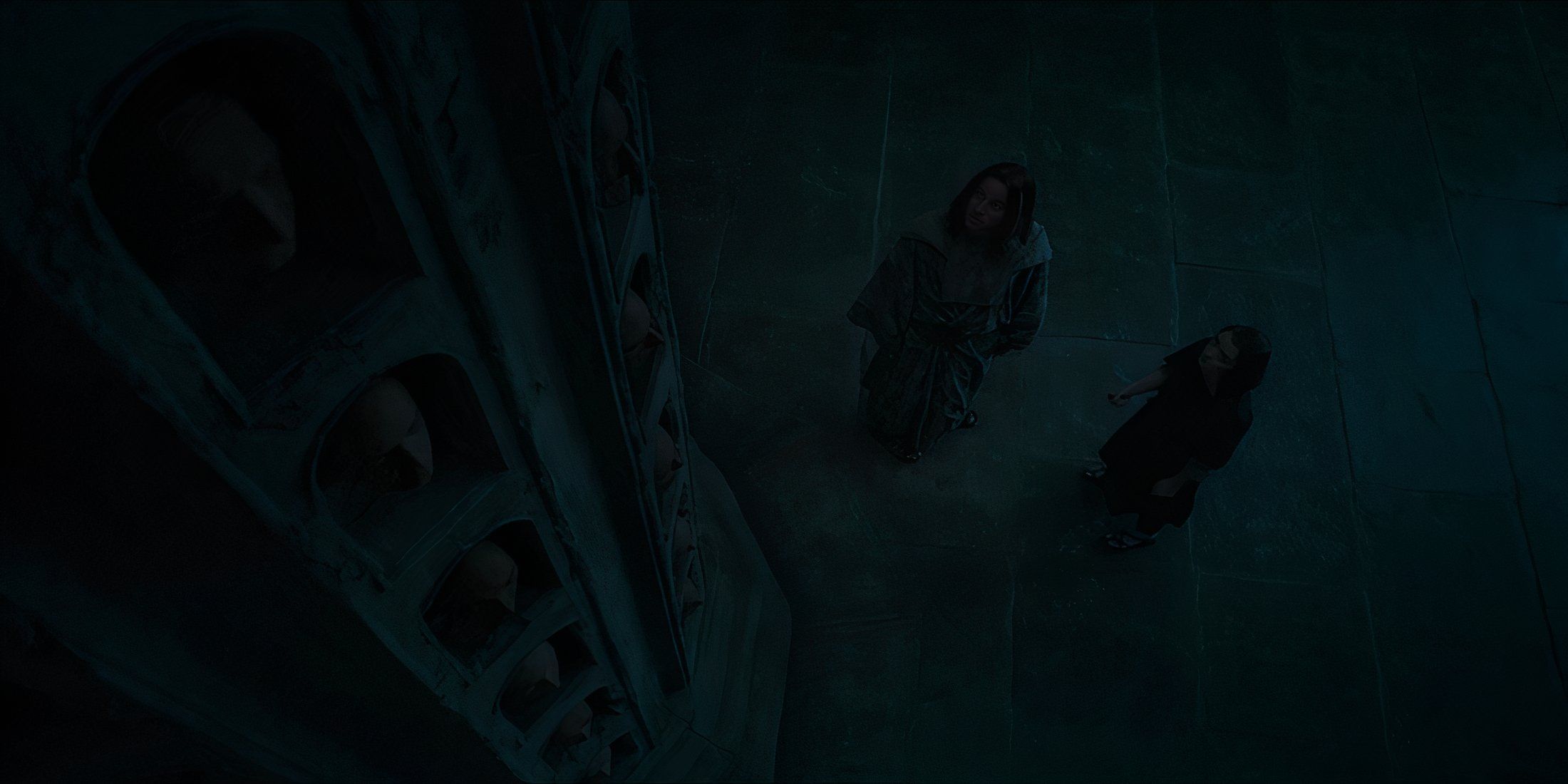 Jaqen H'ghar and Arya Stark staring up at a wall of faces in Game of Thrones