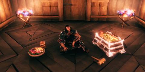 Valheim player sitting in home base with food and treasure chest