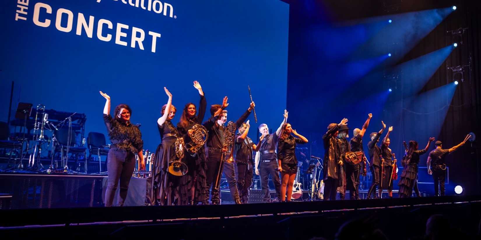 Image of the players for the concert taking a bow, waving to the audience.
