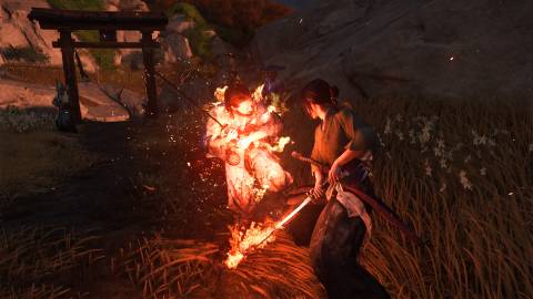 Attacking enemies with a flaming sword in Ghost of Yotei