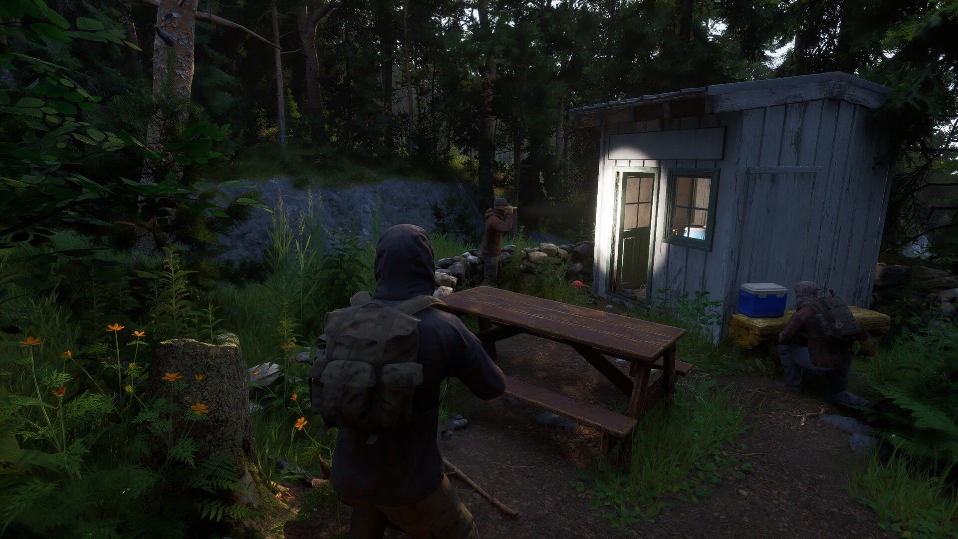 Gubuk dan bangku piknik di Ardem, menunjukkan lingkungan game yang damai namun hancur