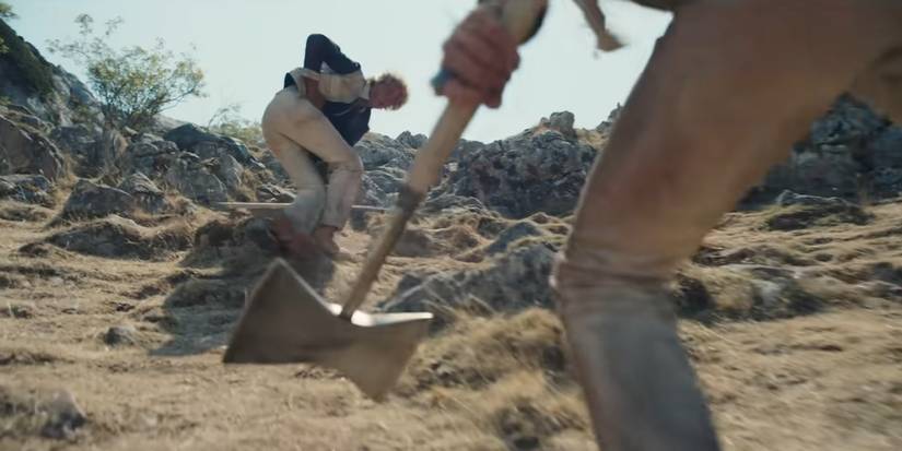 Silka brandishes her axe as she walks toward Haymitch in Sunrise on the Reaping