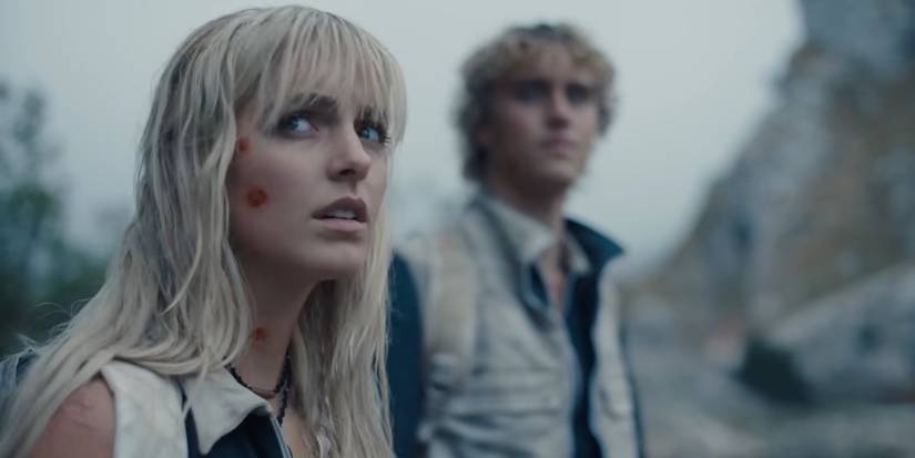 A closeup of Maysilee with Haymitch in the background in Sunrise on the Reaping