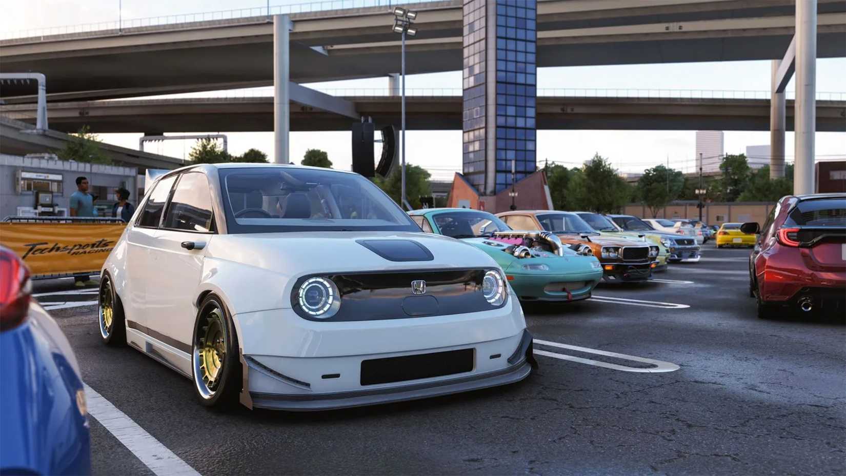 A Honda e. sits in a row of other cars in a parking lot