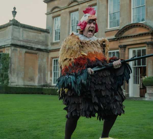 Freddy in the chicken costume holding a gun in The Gentlemen