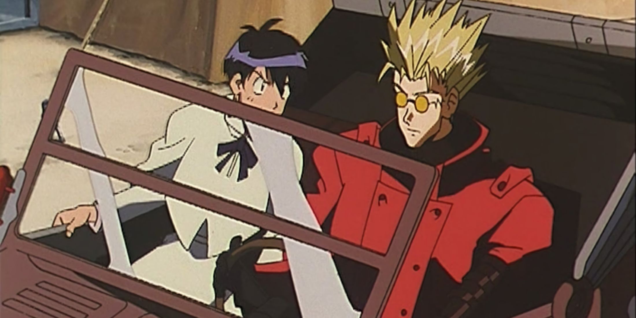Vash and Meryl driving as the woman reprimands him.