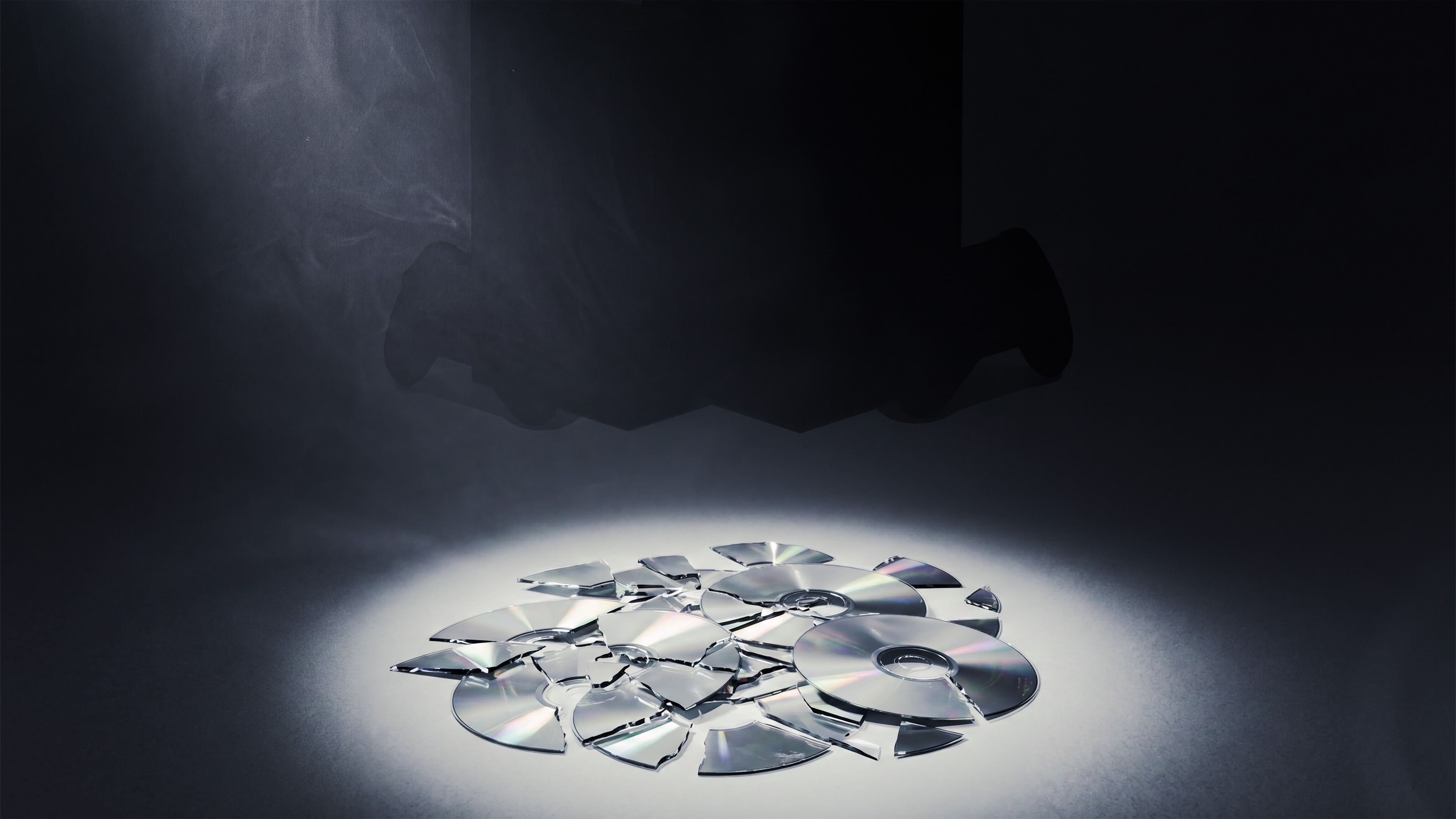 Broken video game disc with Xbox in the background