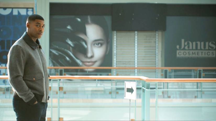 John Stewart standing in front of an advertisement for Janus Cosmetics in Lanterns Episode 3