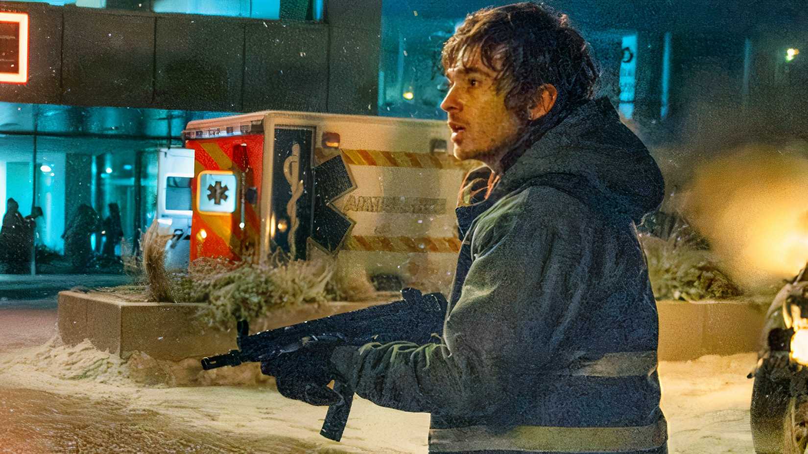 Austin Abrams as Bryan holding a machine gun in front of a hospital as it snows