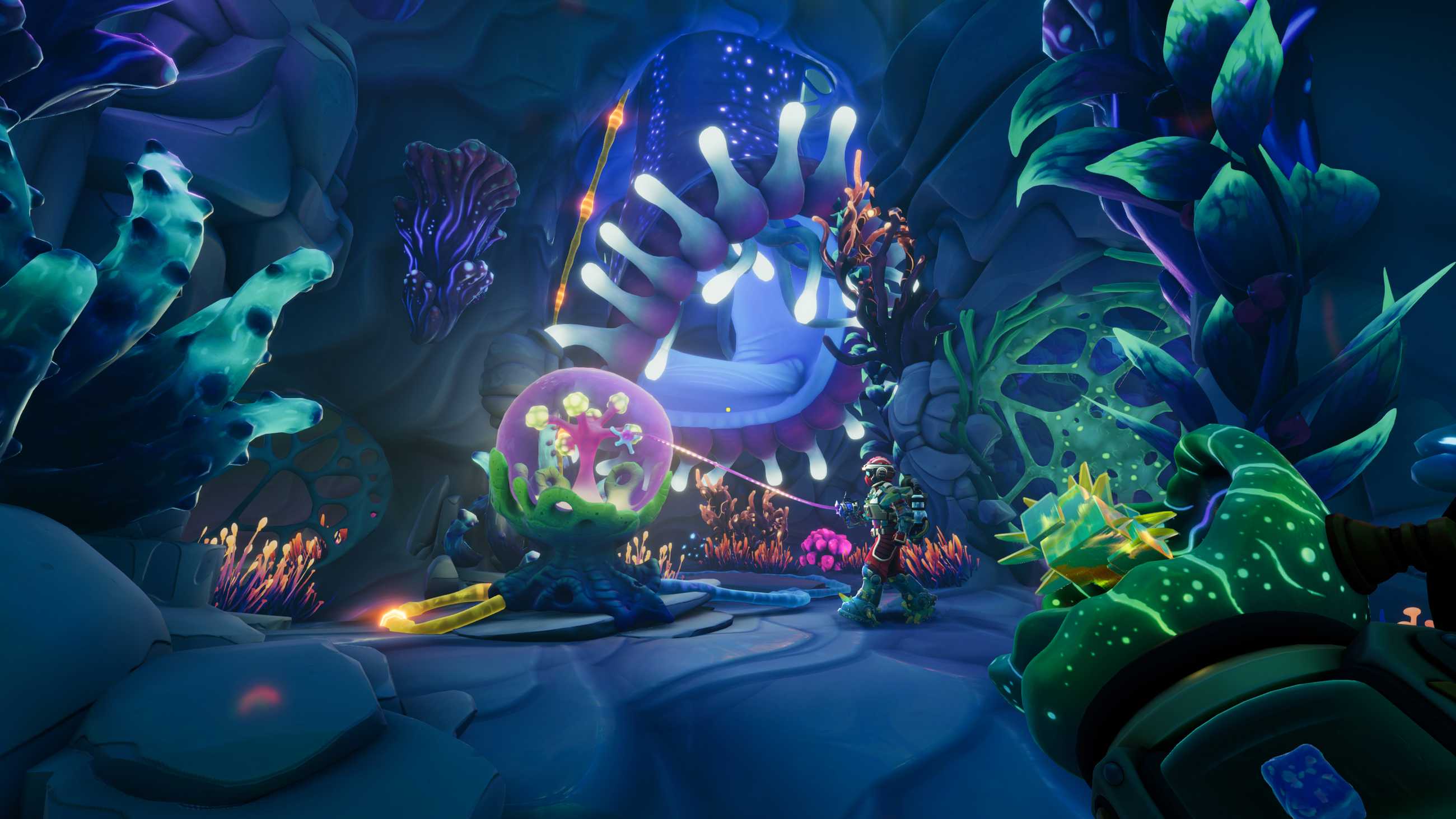 A red-suited Explorer uses a goop glove to hook a glowing alien plant inside a cavern filled with colorful bioluminescent vegetation in We Were Here Tomorrow