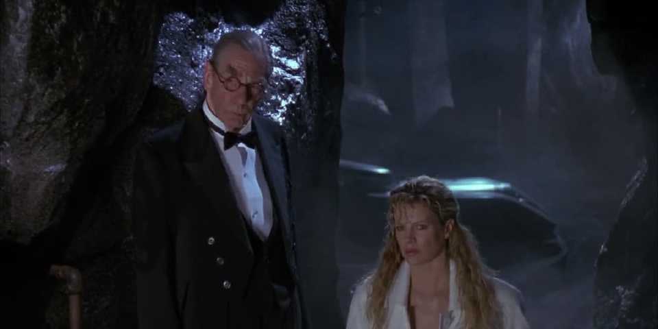 michael-gough-and-kim-basinger-as-alfred-and-vicki-vale-standing-in-the-batcave-and-looking-at-bruce-wayne.jpg