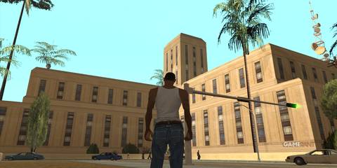 CJ in front of a large building with palm trees in Los Santos in GTA San Andreas