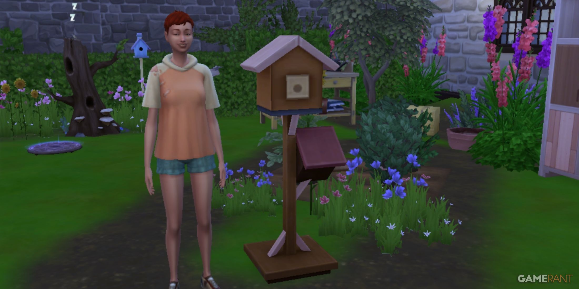 A sim wearing a pink shirt is standing next to a small birdhouse from the sims 4 eco lifestyle with flowers in the background