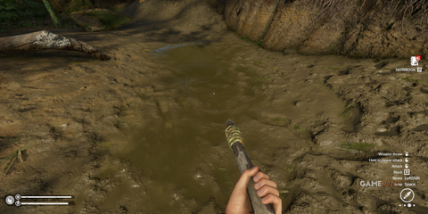 Examining a muddy riverbank while gripping a pointed spear under a clear sky in Green Hell