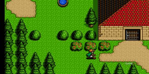 A character walks near bushes and trees outside a house with a red roof in Shining Force 2