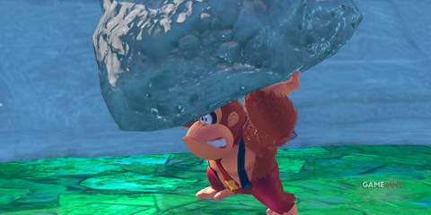 Donkey Kong lifts a giant rock above his head with determination in Donkey Kong Bananza