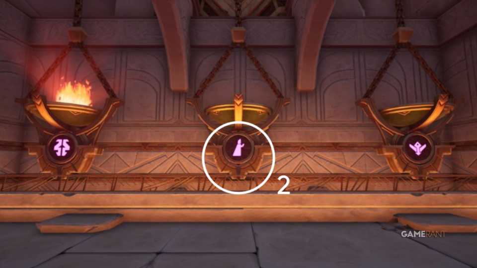 After finding the symbols on the crossbeams, solve the heater puzzle by shooting arrows at these pans to unlock the door to the Flame Temple entrance hall.