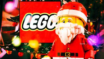A large Santa Claus minifigure in front of a LEGO logo, surrounded by colorful holiday lights, with a Christmas tree visible in the background.